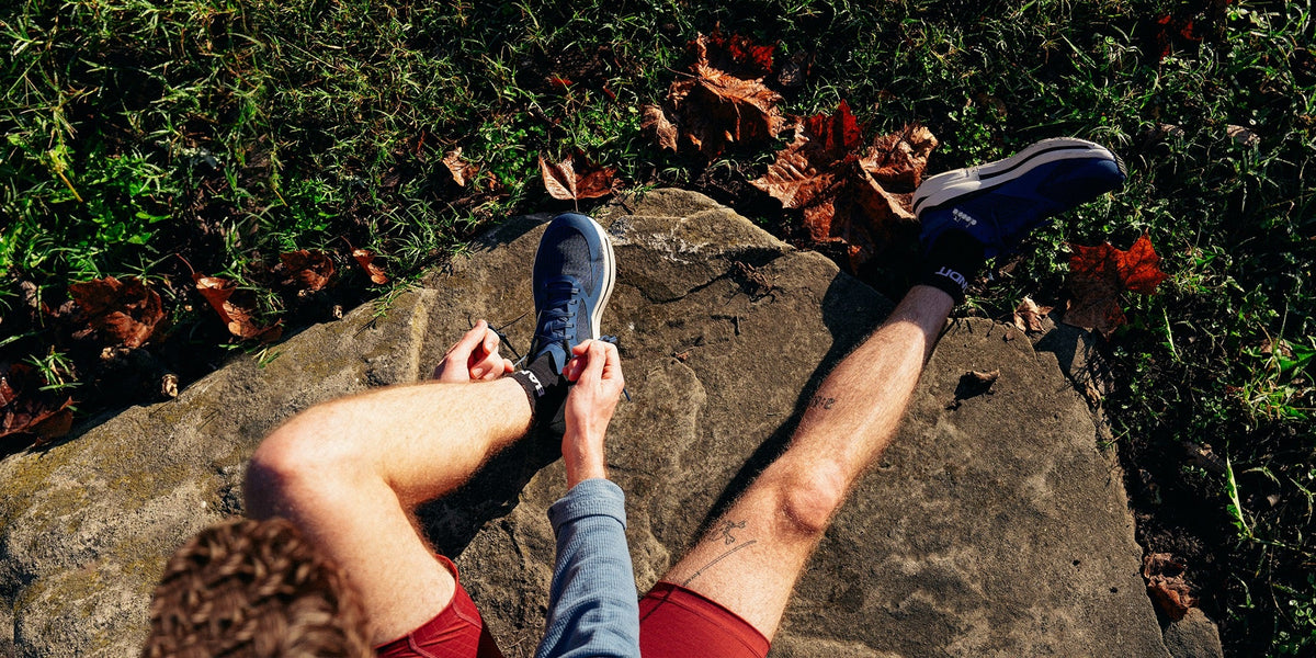 A male runner does up his shoe laces in the morning sunlight