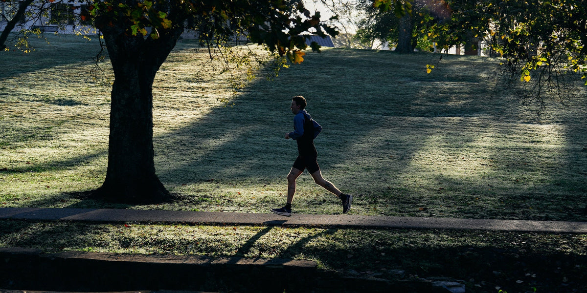 A man runs through a park at sunrise