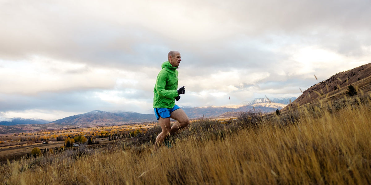 A man runs up a trail on the side of a mountain