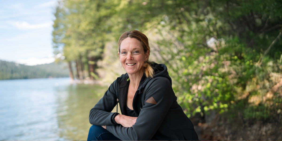 Dr. Stacy Sims sits beside a lake