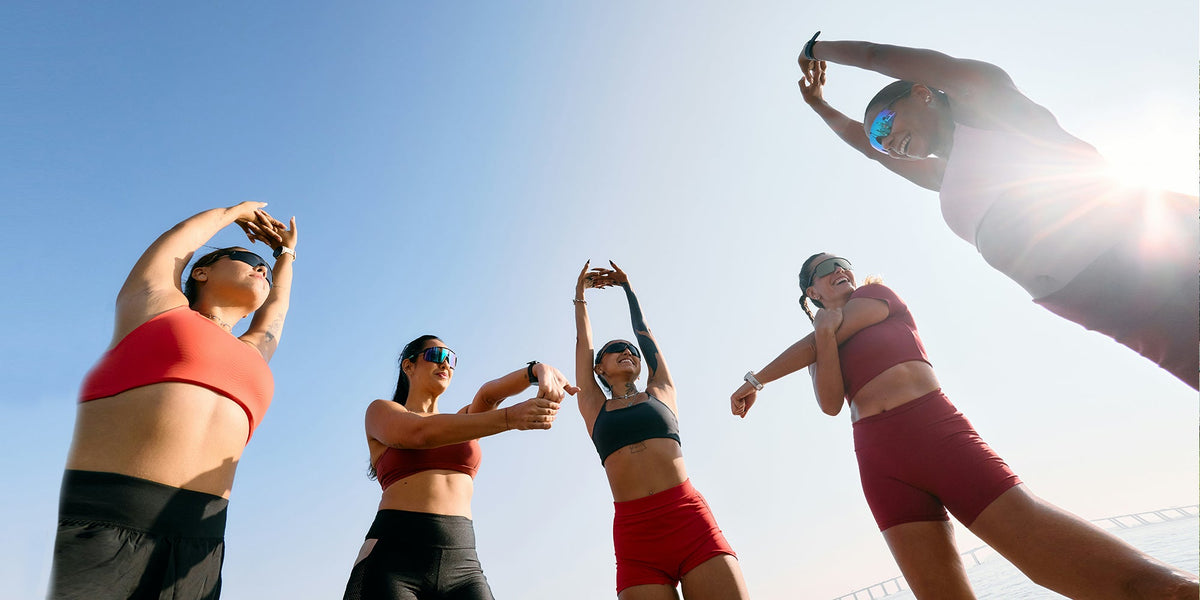 a group of five women stand in a circle stretching