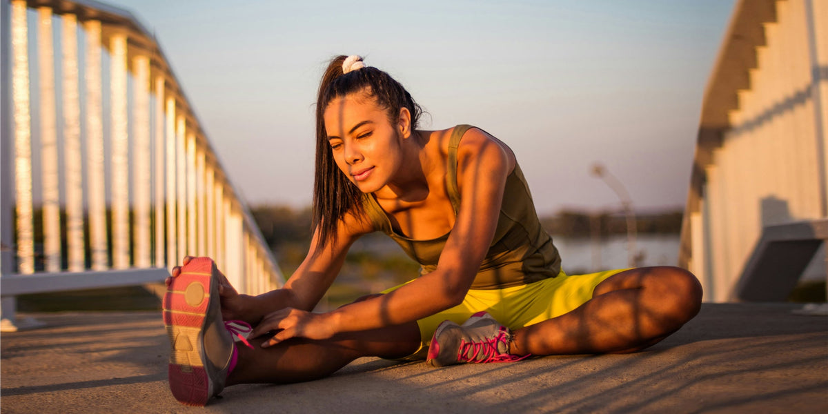 A woman stretches her hamstrings in the morning light