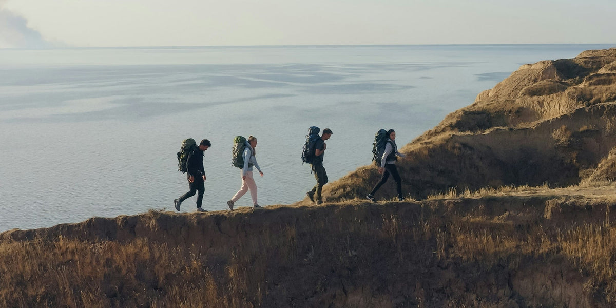 a group of men and women hike along a coastal path