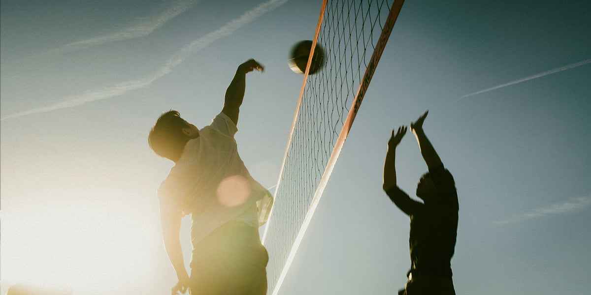 two men play beach volleyball