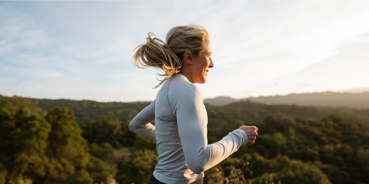 a woman with blonde hair runs towards the sunrise