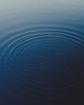 Aerial view of calm water with concentric ripples representing purity without compromise, showing how Momentous Creatine is washed with reverse osmosis water through a pharmaceutical manufacturing process instead of chemical washing