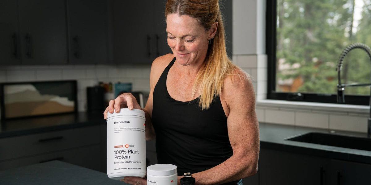 Dr Stacy Sims with a tub of Momentous Plant Protein