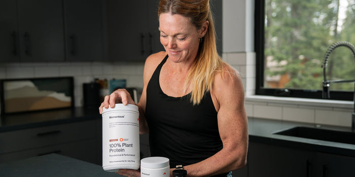 Dr Stacy Sims with a tub of Momentous Plant Protein