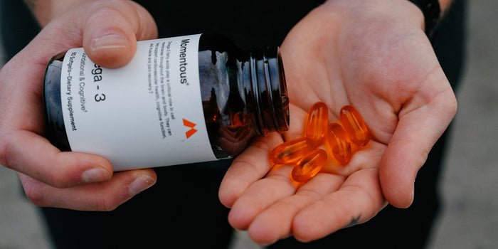 A person pours some Momentous Omega-3 capsules into their hand