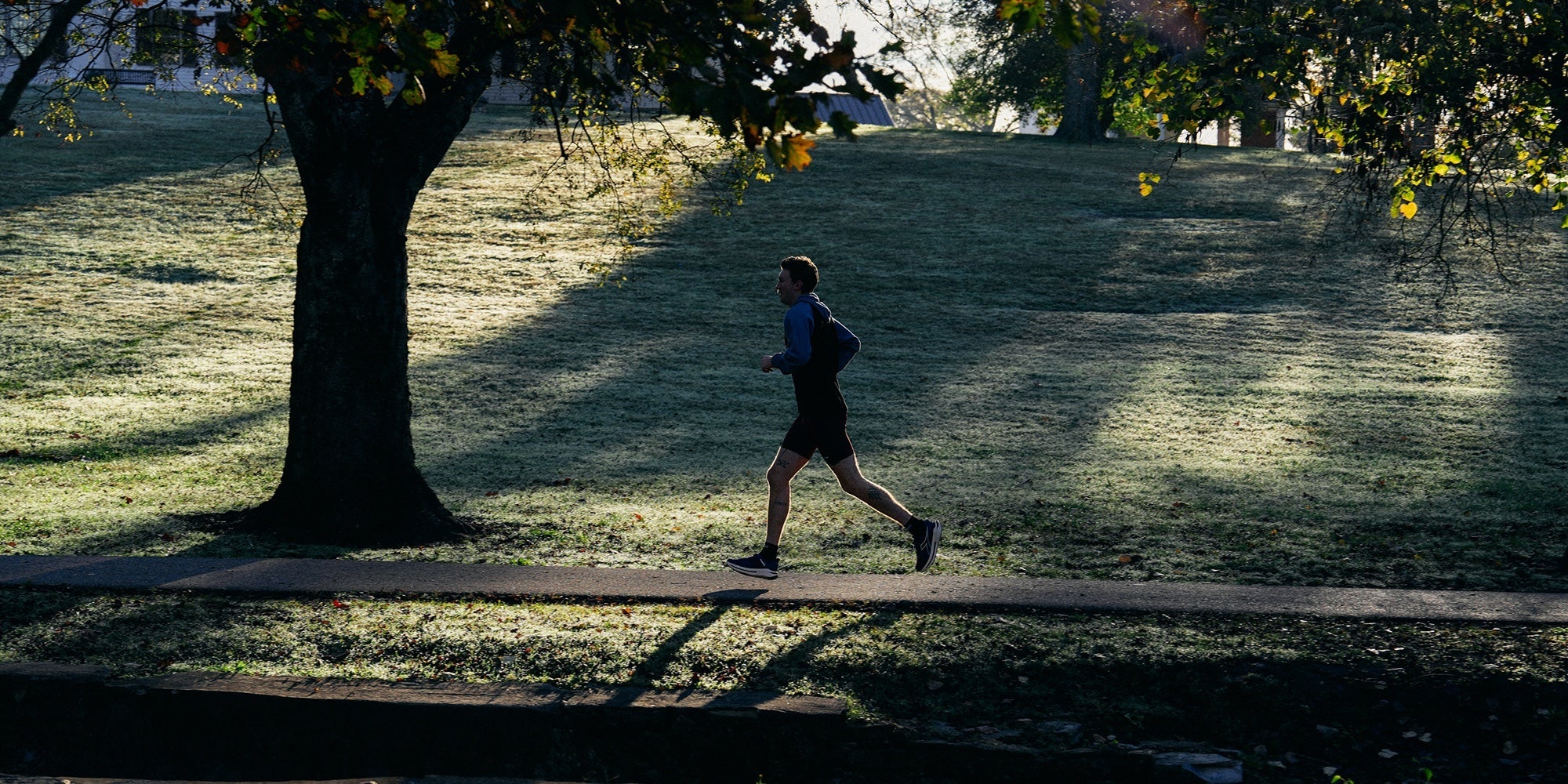 A man runs through a park at sunrise