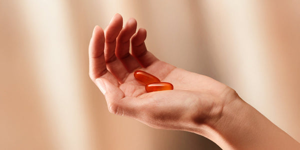 A person's hand holding Omega-3 supplement capsules