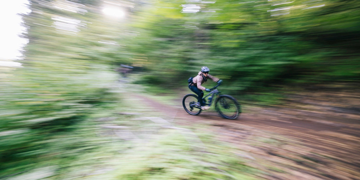 a woman rides a mountain bike downhill 