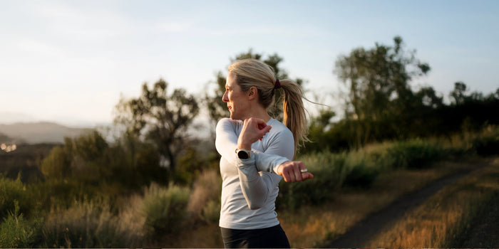 A blonde woman looks to the horizon as she stretches her right arm across her body
