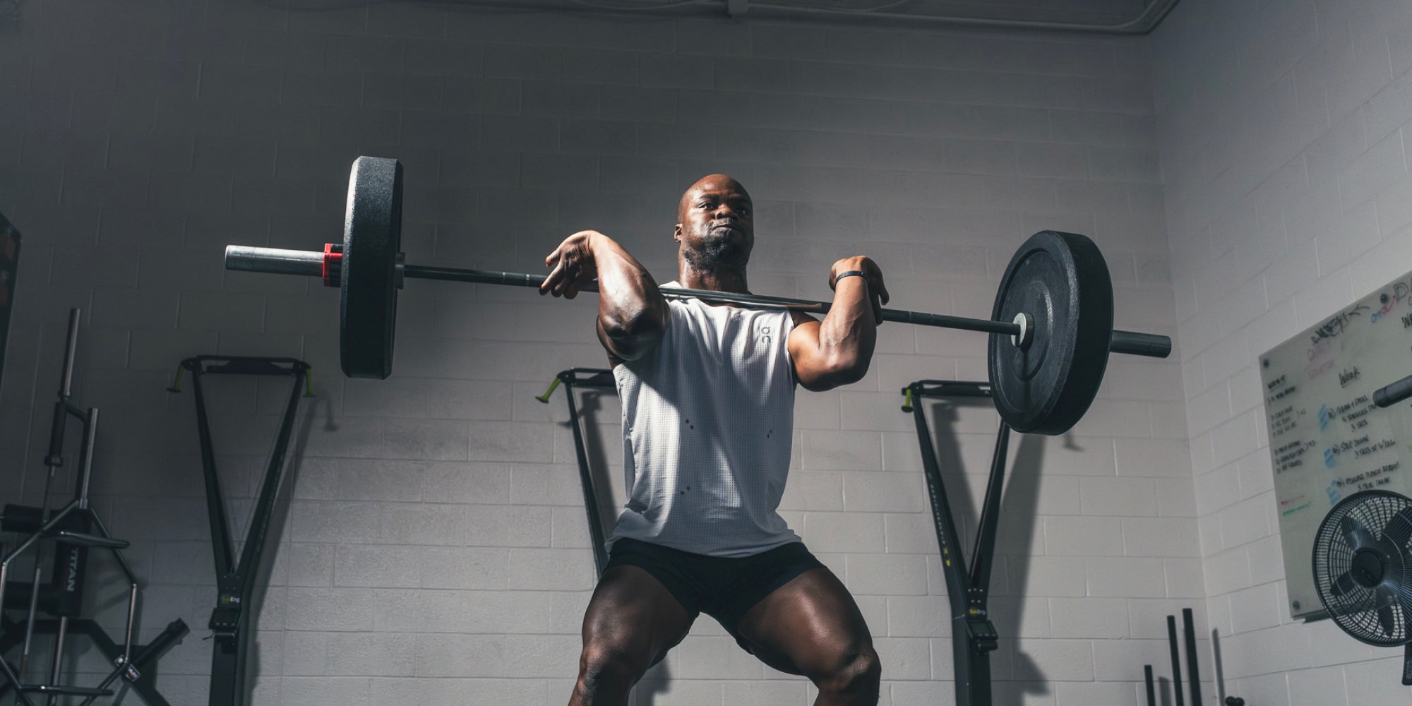 A strong male athlete lifts a heavy barbell in the gym