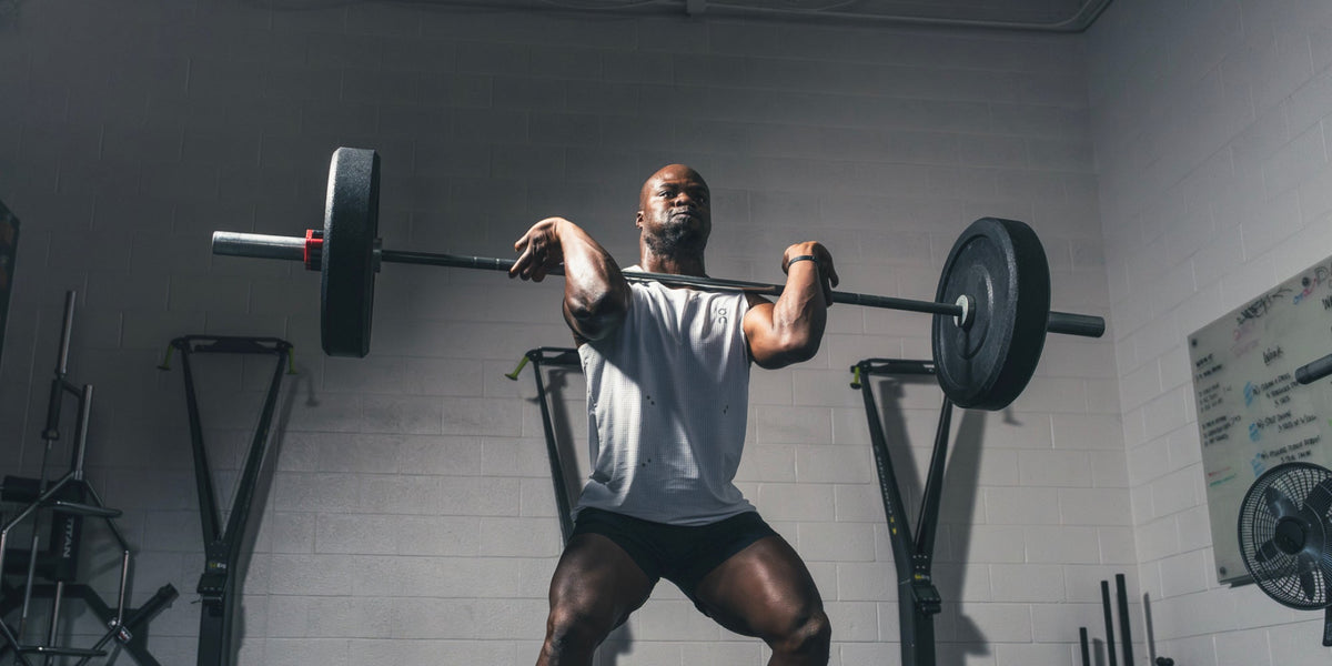 A strong male athlete lifts a heavy barbell in the gym