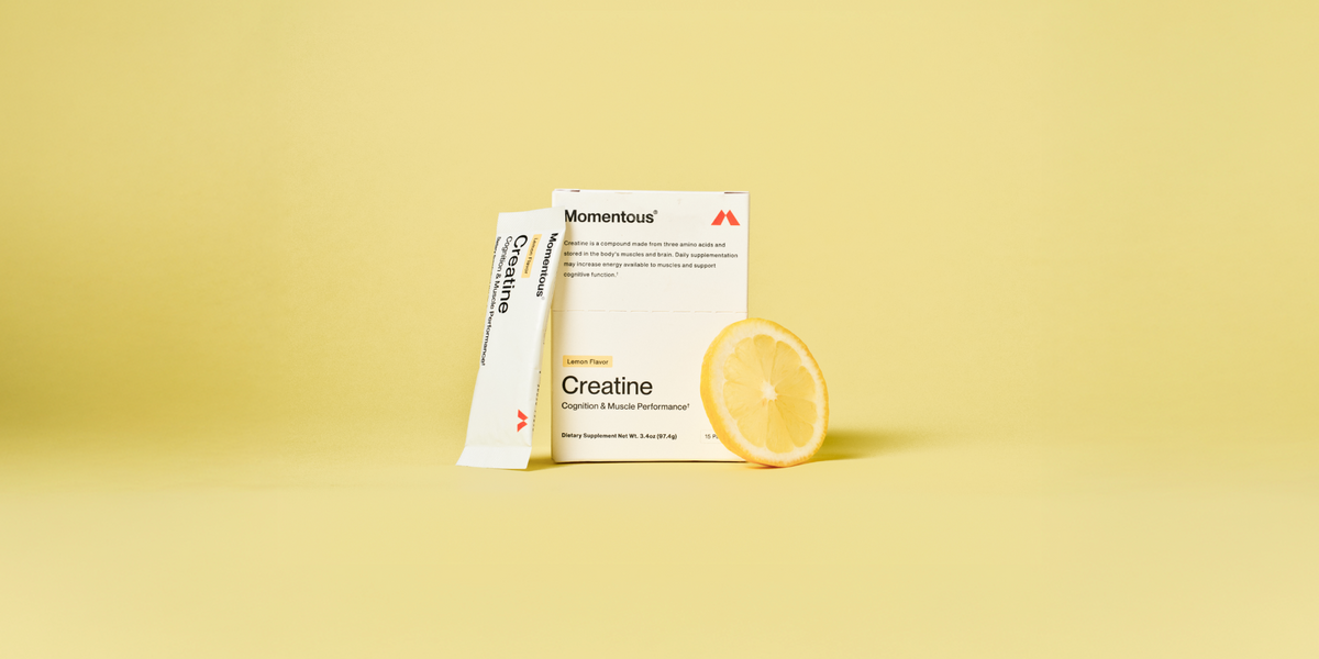 A lemon flavor creatine travel pack, a box of creatine travel packs, and a slice of lemon