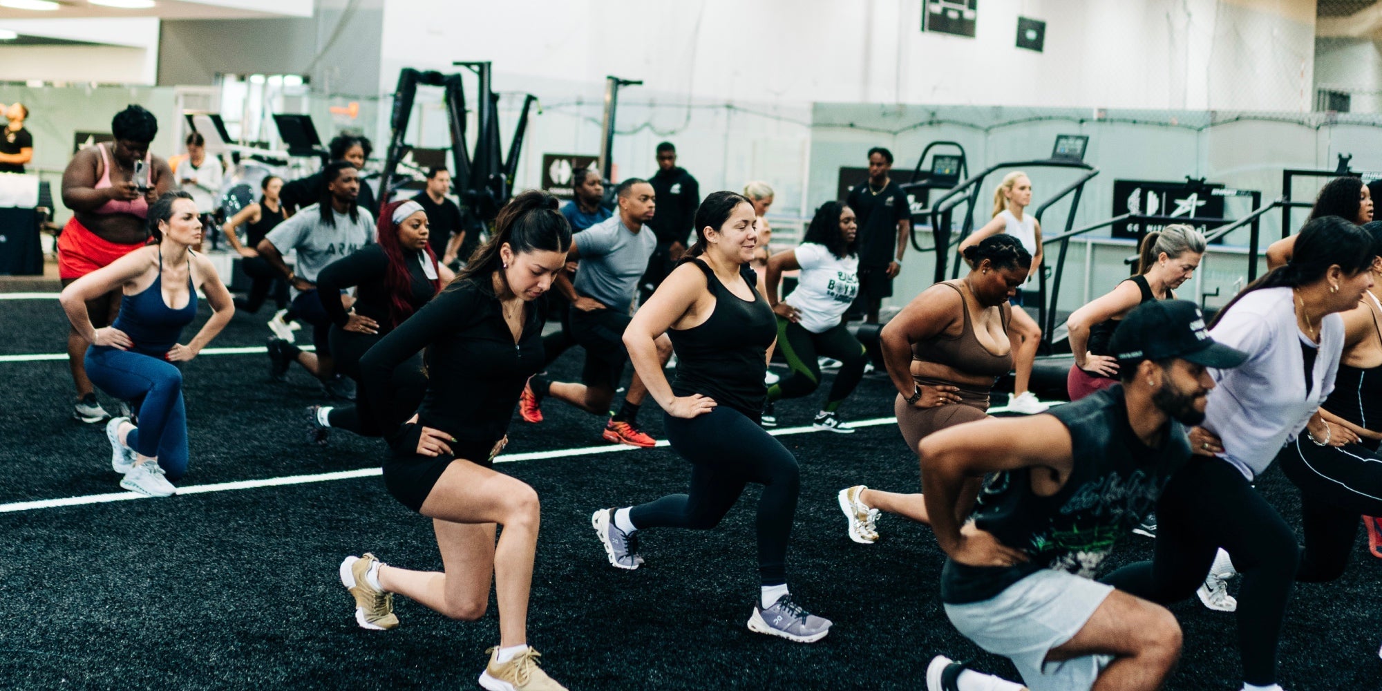 A group of men and women do lunges in a group exercise class