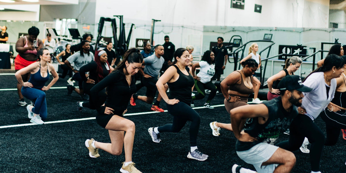 A group of men and women do lunges in a group exercise class