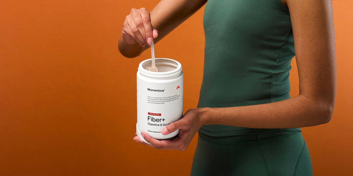 A woman holds a canister of Momentous Fiber+