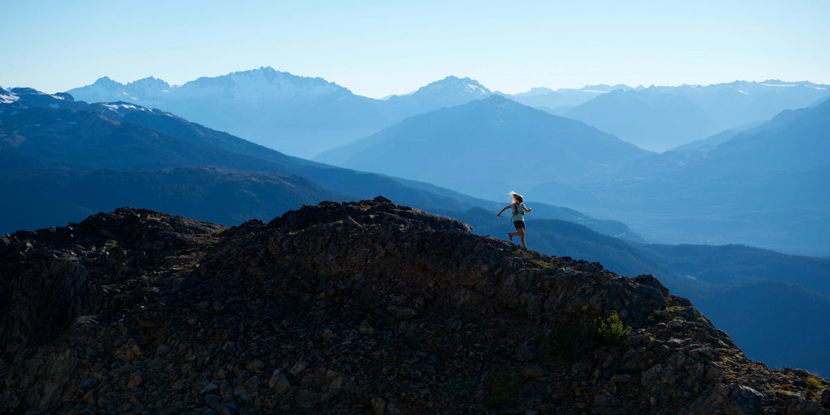 a woman running on top of mountain 