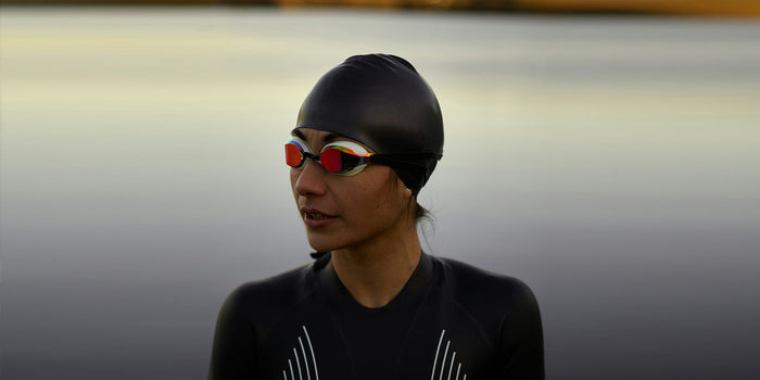 A female athlete in a wetsuit wearing swim cap and goggles