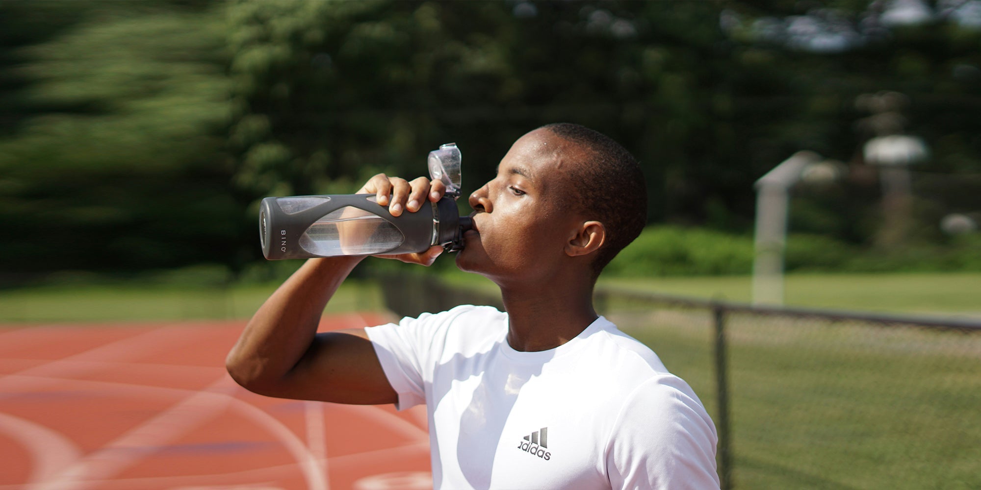 a male athlete drinks from a water bottle