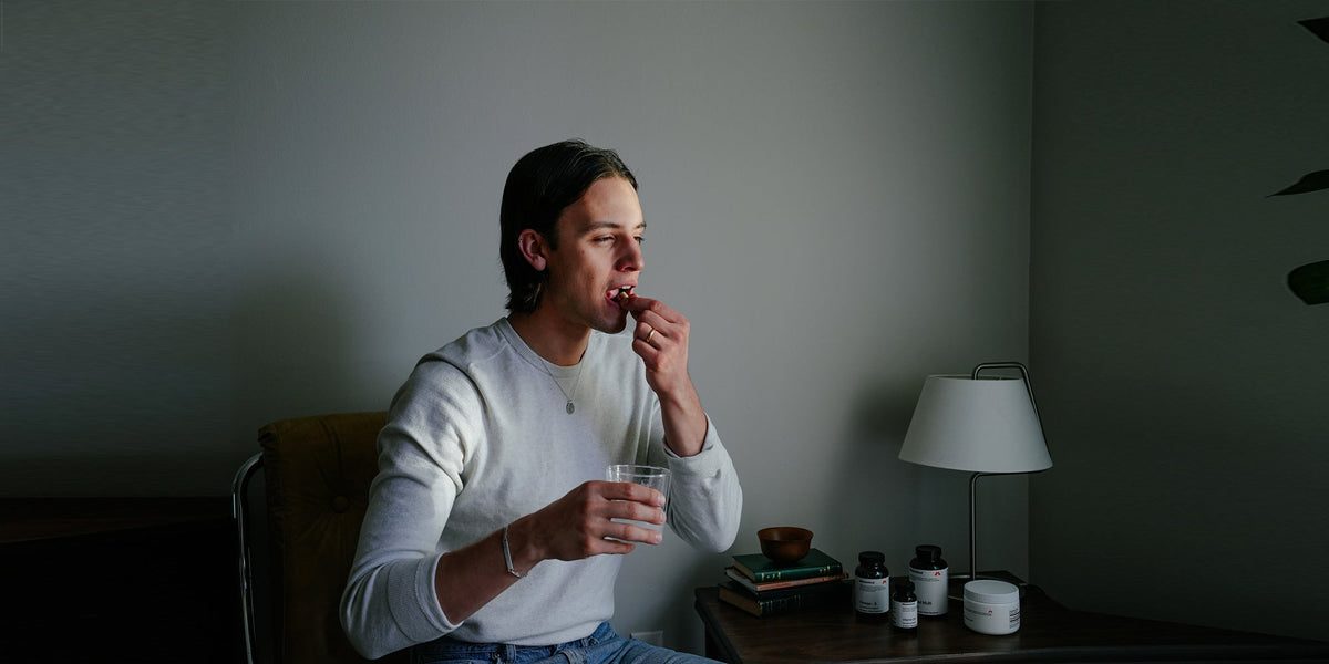 a young man takes a tablet while holding a glass of water
