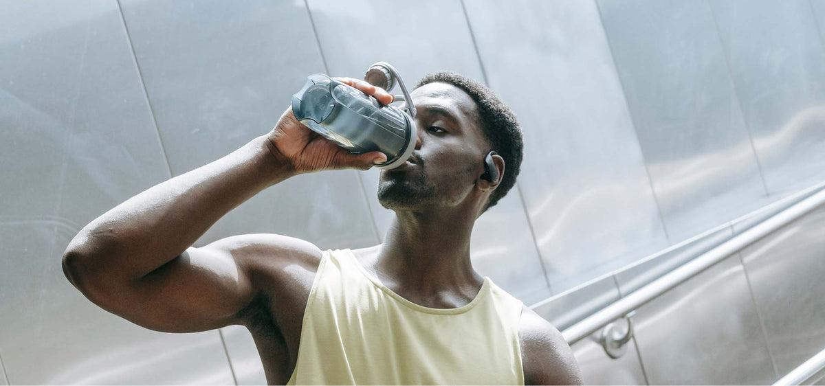 An athletic man drinking from a water bottle