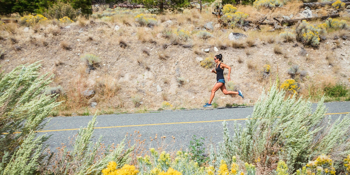 An athletic woman runs downhill on a road