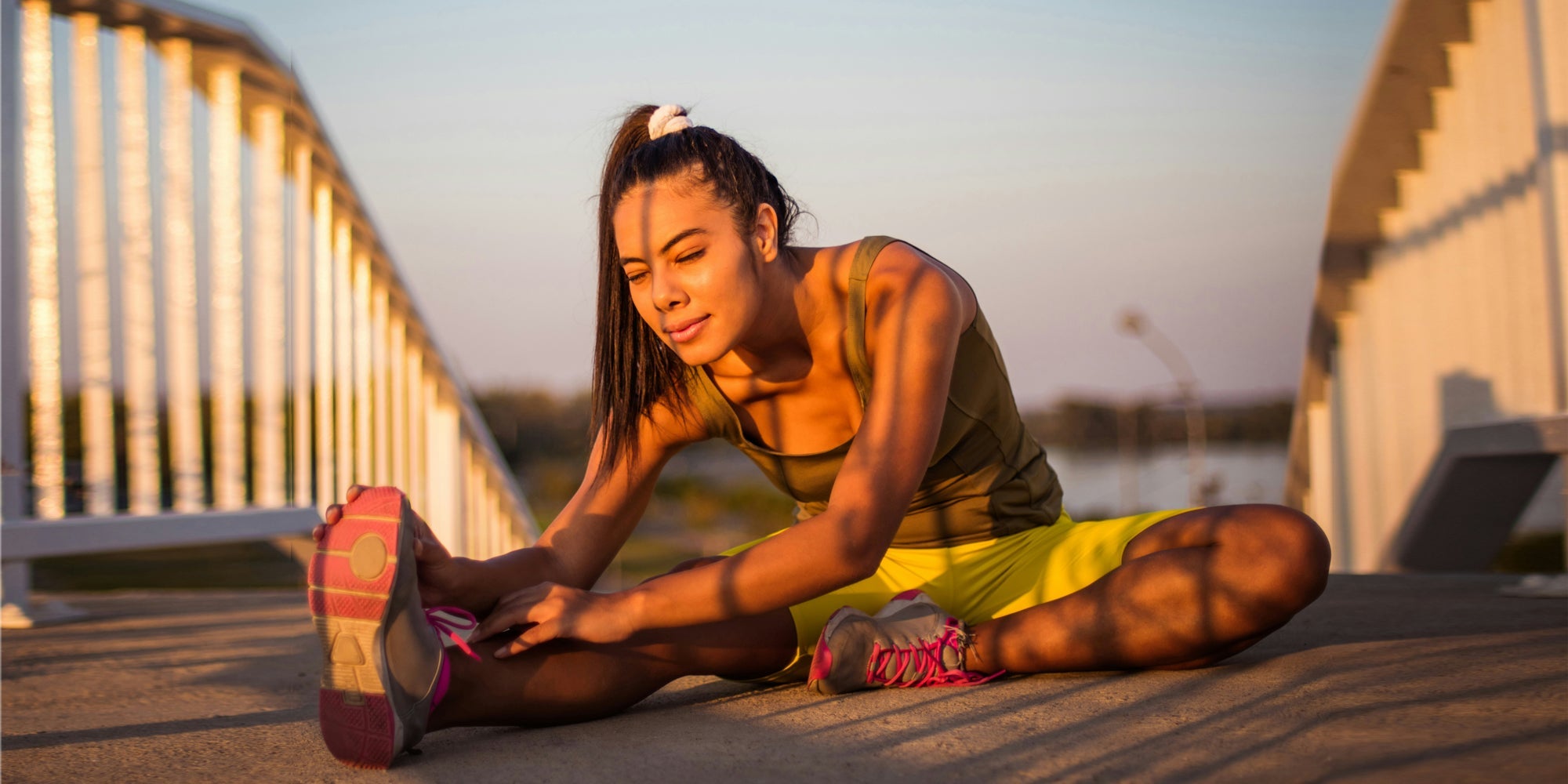 A woman stretches her hamstrings in the morning light