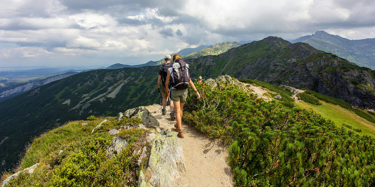 A man and woman hike along a mountain trail