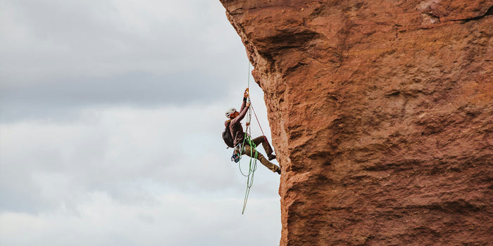 a male athlete climbs up a rockface