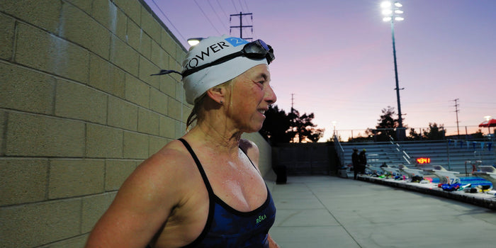 A woman stands on pool deck after a swim workout