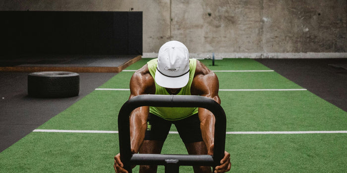 A male athlete pushes a sled on the track in the gym