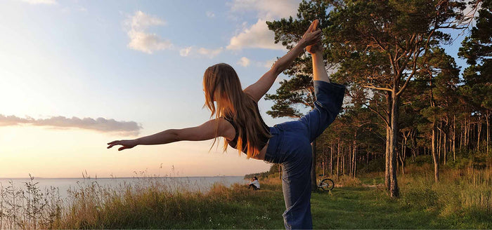 Woman practicing yoga outdoors at sunset in a scenic landscape, representing joint health and flexibility supported by collagen.