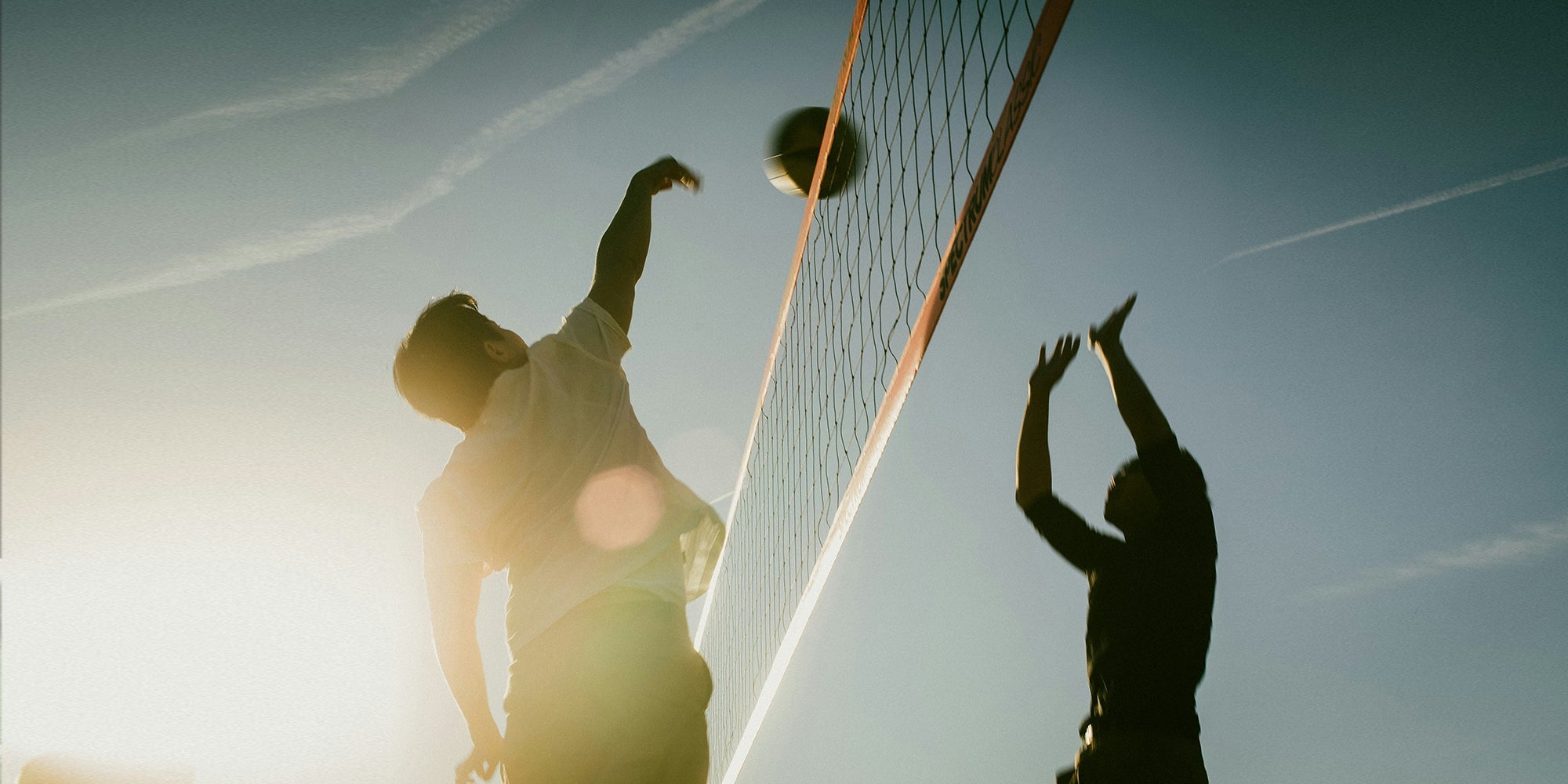 two men play beach volleyball