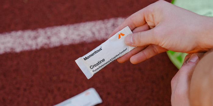 athlete at track holding creatine travel pack
