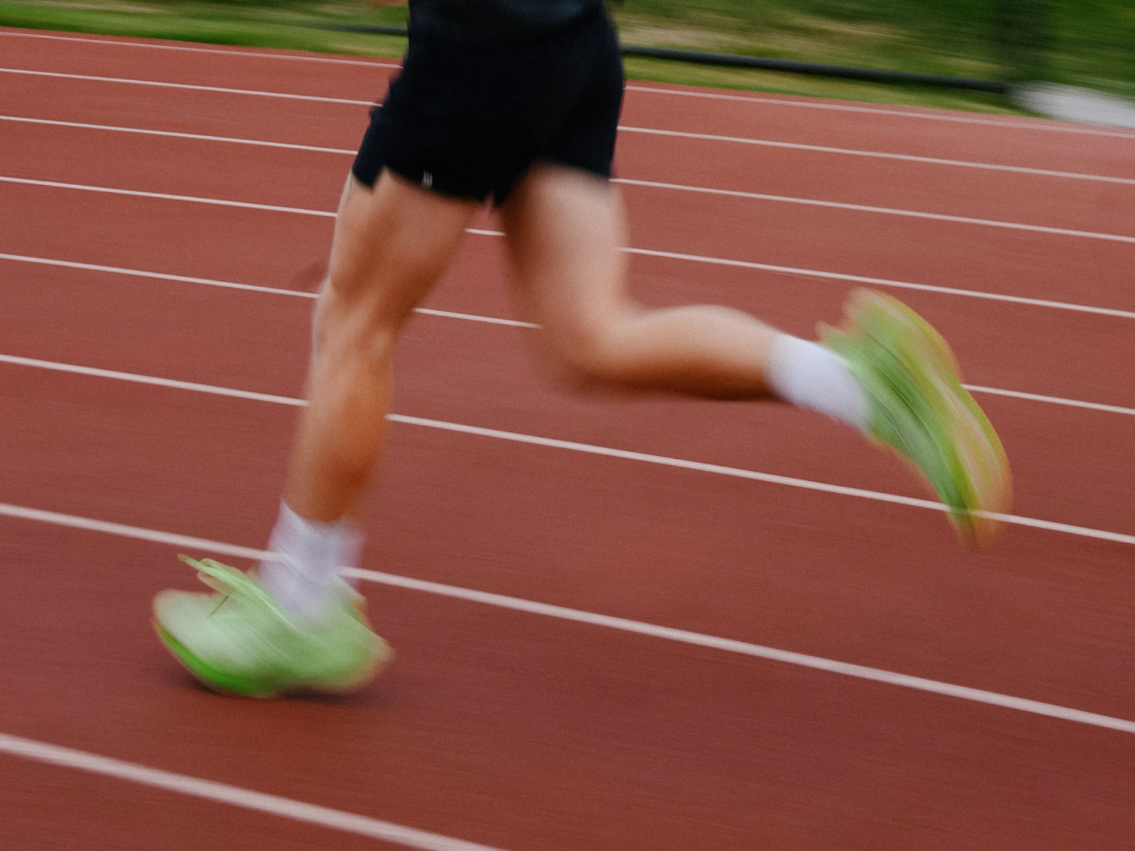 “Runner’s legs in motion on a track wearing bright running shoes.”