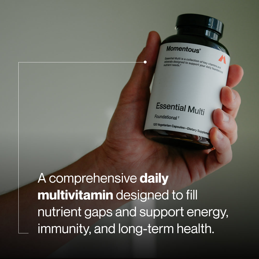 A comprehensive daily multivitamin designed to fill nutrient gaps and support energy, immunity, and long-term health. Image shows a hand holding a Momentous Essential Multi bottle with label text: “Momentous. Essential Multi. Foundational†. 120 Vegetarian Capsules—Dietary Supplement.”