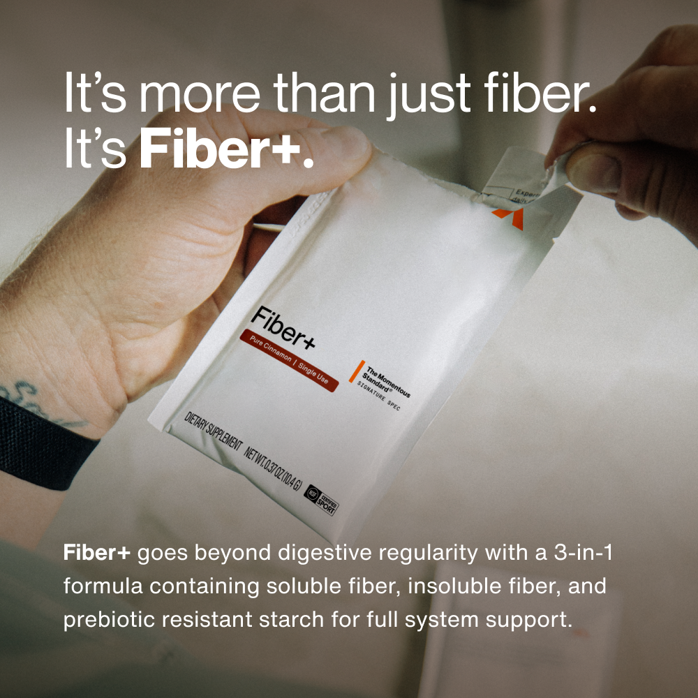 Hand holding white Fiber+ travel pack sachet with orange accent label.