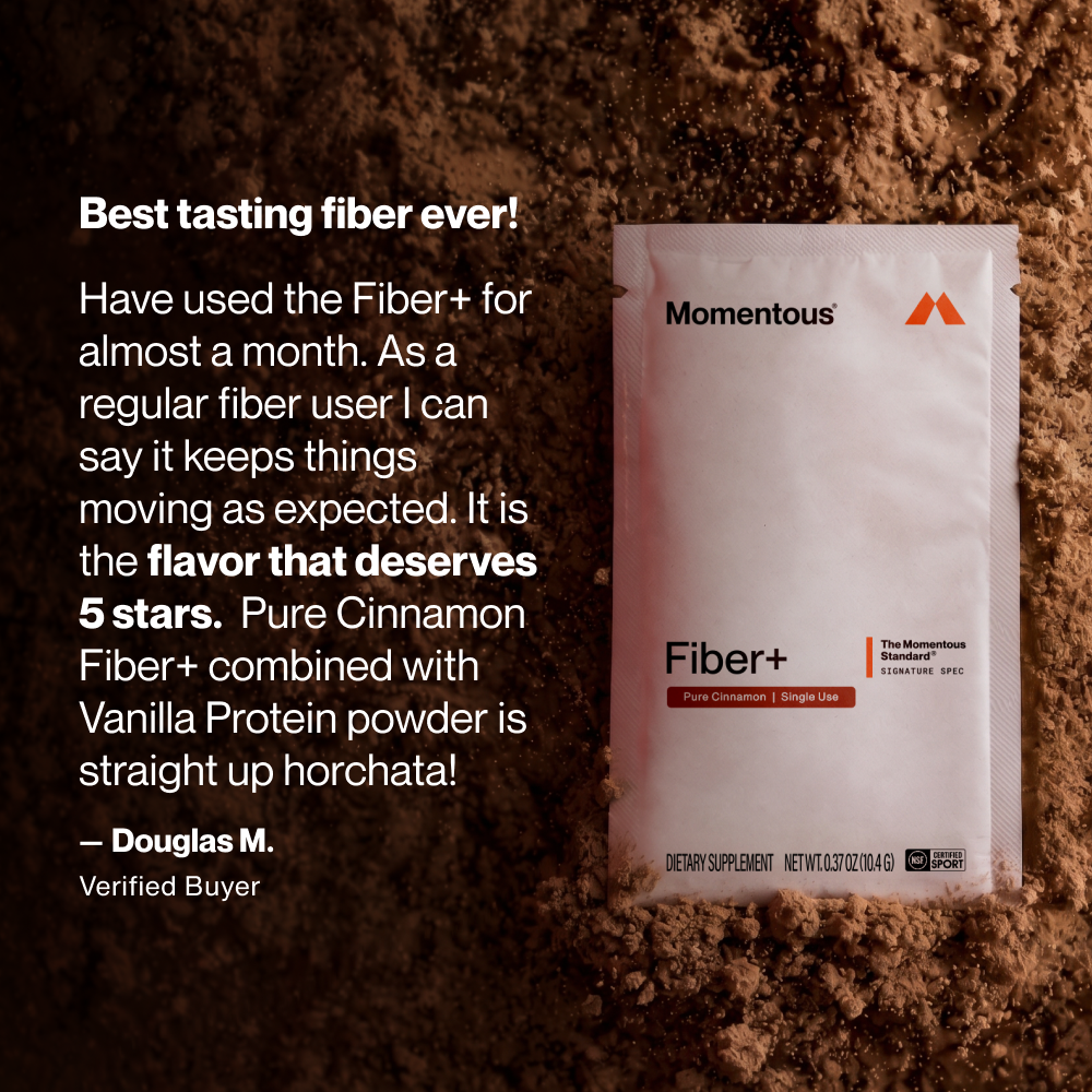 White packet of Momentous Fiber+ Pure Cinnamon dietary supplement labeled as single use travel pack on brown textured backgro