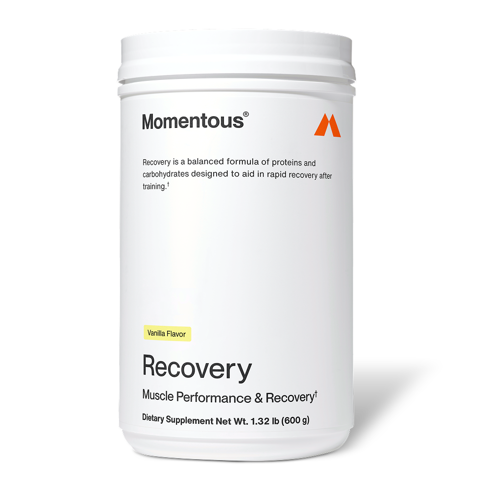 White Momentous Recovery container labeled “Vanilla Flavor.” Text reads: “Momentous. Recovery is a balanced formula of proteins and carbohydrates designed to aid in rapid recovery after training. Recovery. Muscle Performance & Recovery†. Dietary Supplement Net Wt. 1.32 lb (600 g).”