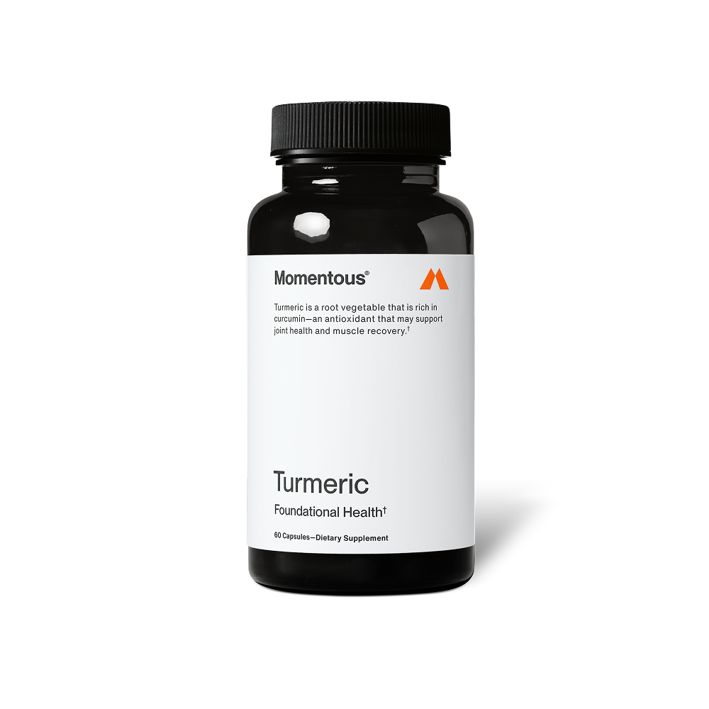 A black bottle of Momentous Turmeric dietary supplement is centered on a black background with a white label. Text on the label reads: “Momentous®” “Turmeric is a root vegetable that is rich in curcumin—an antioxidant that may support joint health and muscle recovery.†” “Turmeric” “Foundational Health†” “60 Capsules—Dietary Supplement”