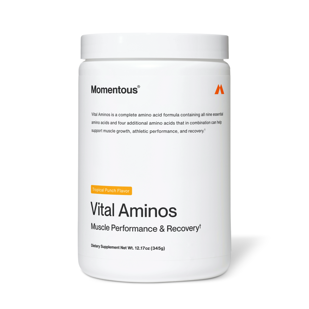 White container labeled “Momentous Vital Aminos – Muscle Performance & Recovery†.” Text notes it is a complete amino acid formula containing all nine essential amino acids plus four additional amino acids to support muscle growth, athletic performance, and recovery. Tropical Punch flavor. Net weight 12.17 oz (345 g).